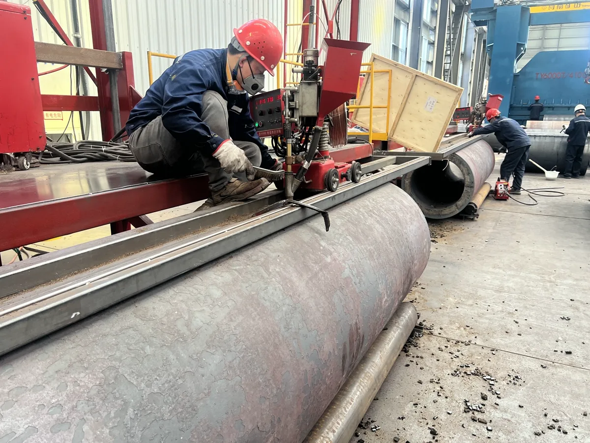Worker welding a rolled steel cylinder